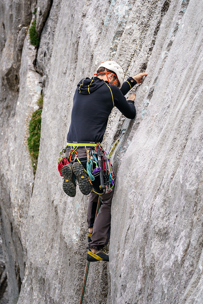 male alpinist climbing up the rocky route