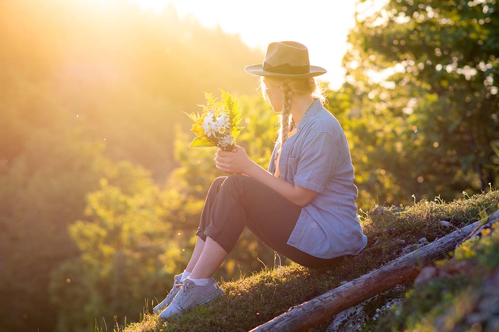 female with flower boquet in her hands backlit by the evening sun